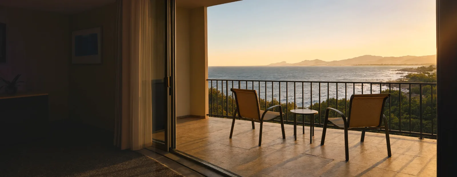 An Empty Resort Balcony At Golden Hour, Two Patio Chairs And A Small Table Facing The Ocean